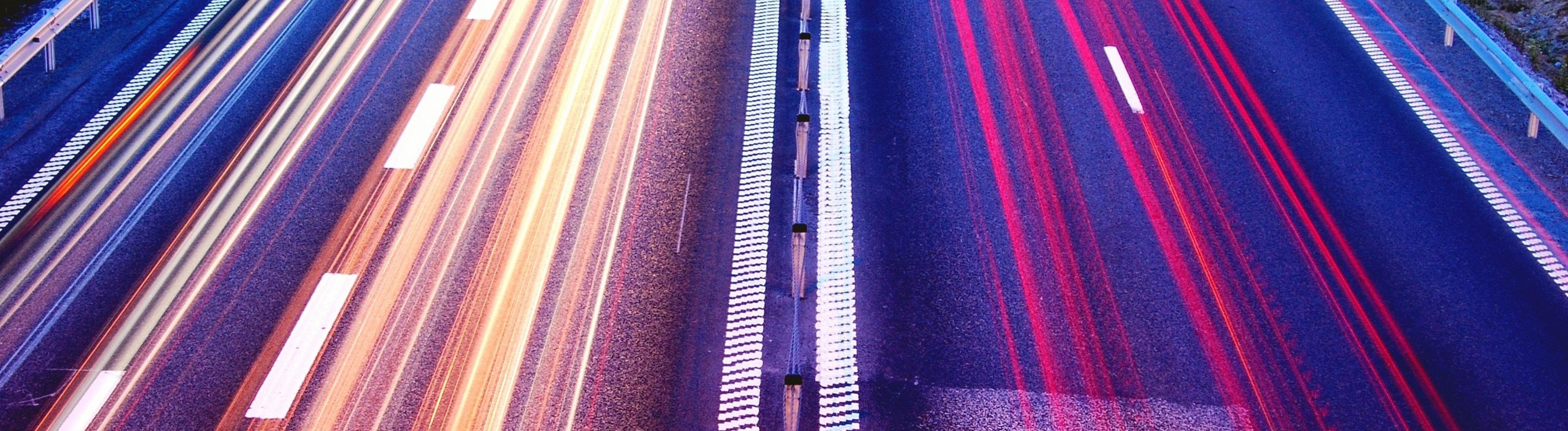 Lange belichtete Fahrbahnen der Autobahn, sodass Lichtlinien in Gelb und Rot entstehen.