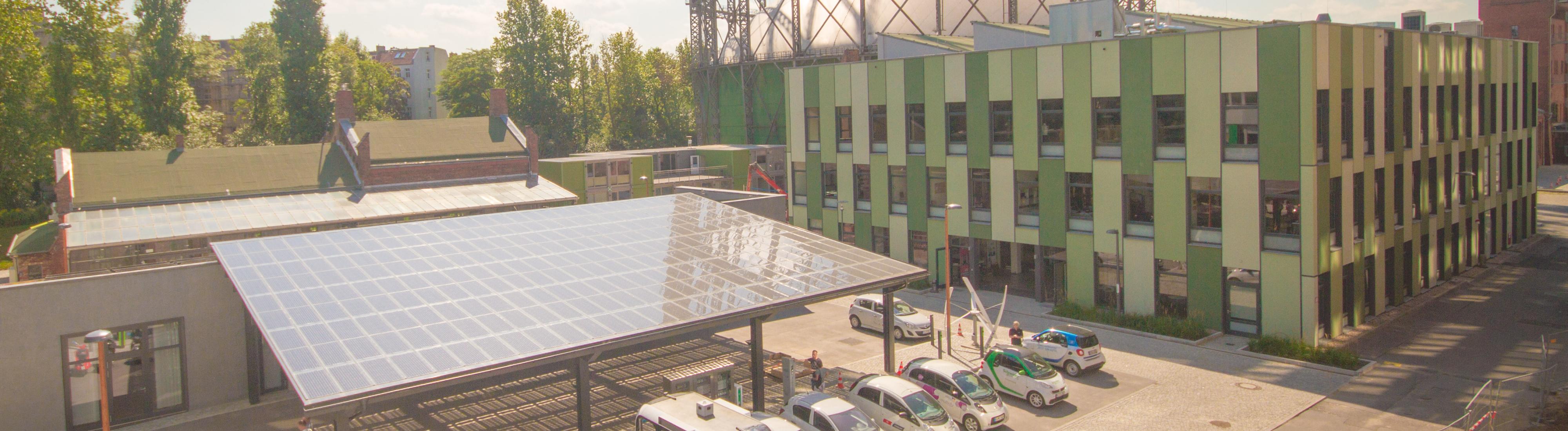 Neben dem alten Gasometer auf dem EUREF-Campus steht eine Überdachung für Elektrofahrzeuge, auf der Solarpanele angebracht sind.